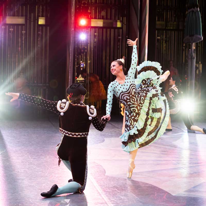Juliet Prine dances on stage in a swirling brown and blue skirt.