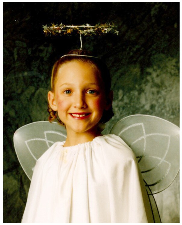 Elizabeth Murphy as a young dancer wearing a white angel costume with wings and a golden halo.