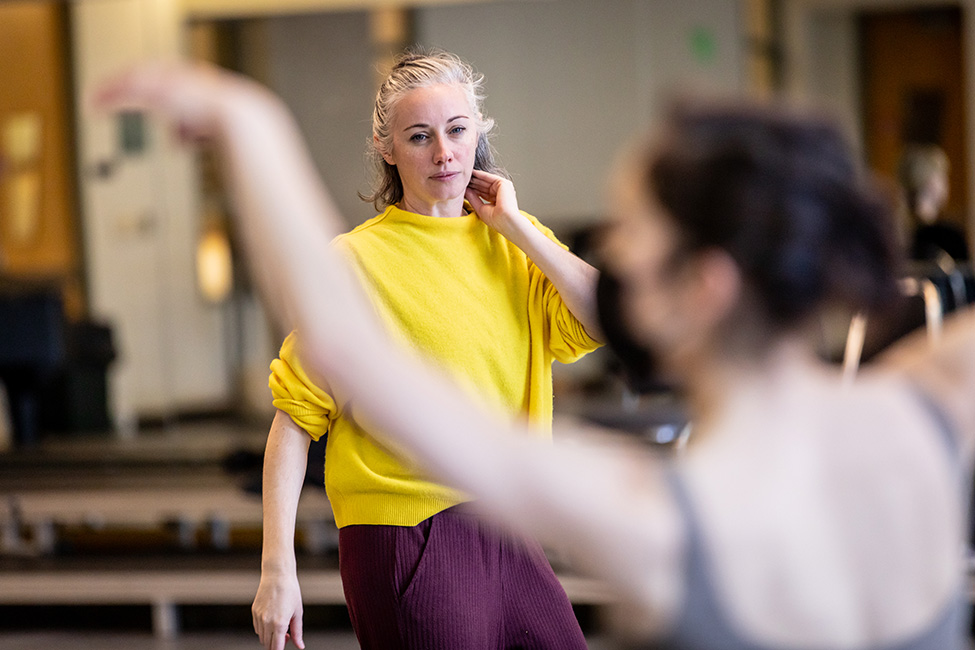 TheWindow_Rowe_rehearsal_LT_009 Dani Rowe, wearing a yellow sweater, carefully observes a dancer in rehearsal.