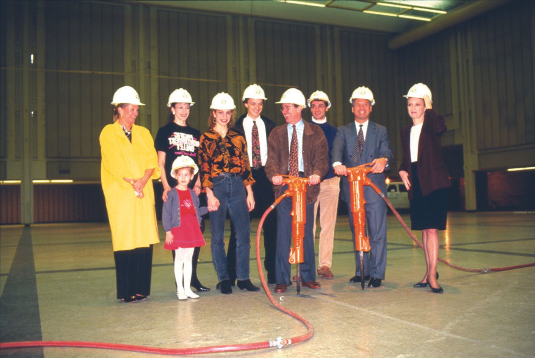 A group of PNB executives, board members, and dancers pose with construction hats and jack hammers during renovations at the Phelps Center.